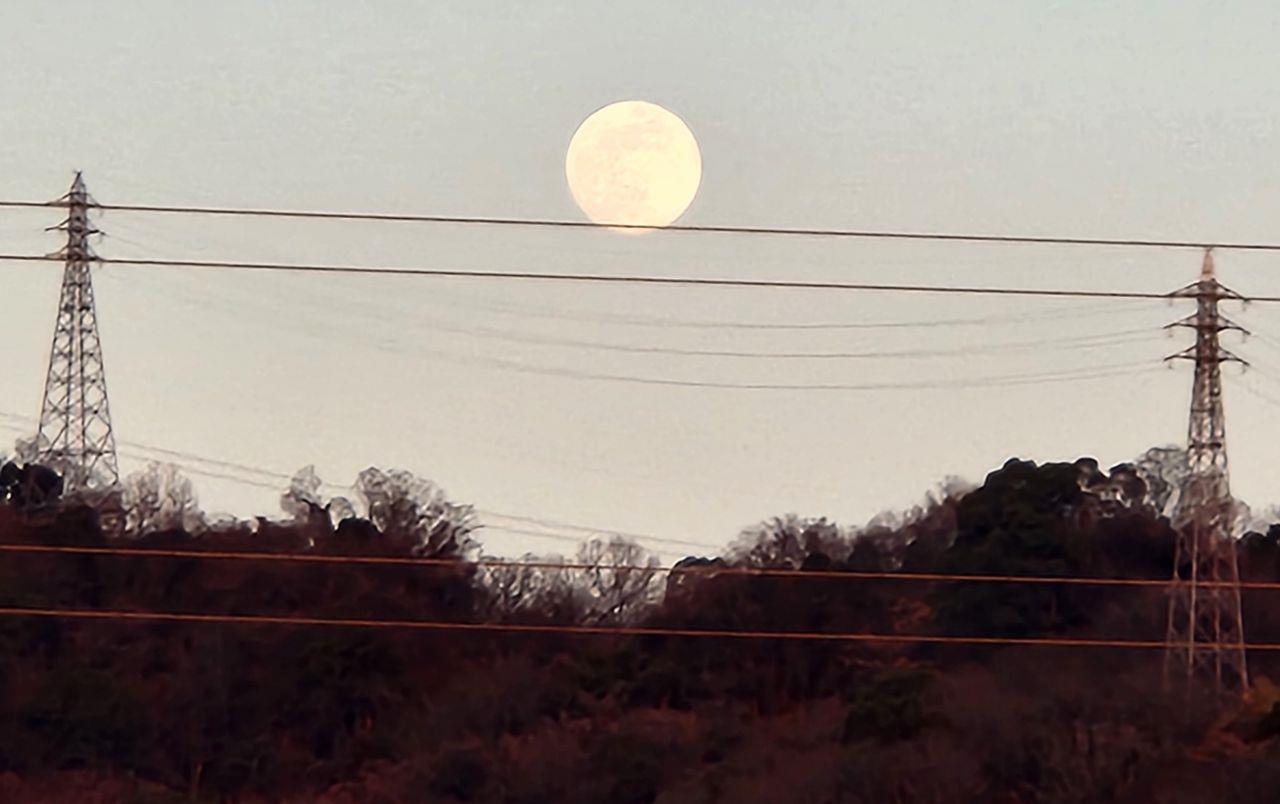 鉄塔と鉄塔の間に満月が浮かんでいる写真