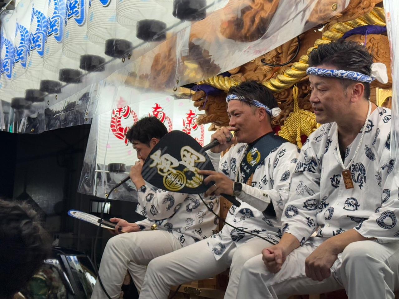 だんじりに乗って歌う人の写真