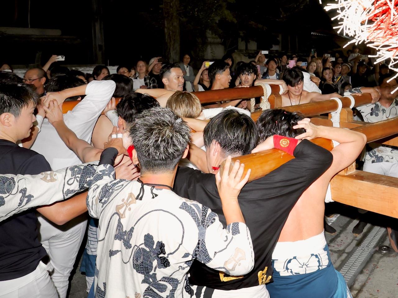 大勢の人が布団太鼓を担ぐ写真