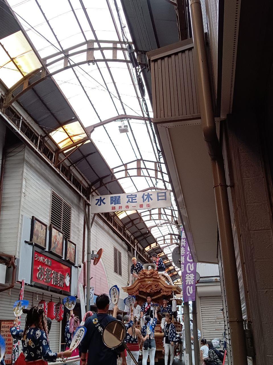商店街の中をだんじりが通過している写真