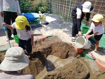 バケツ一杯に水を汲んで作った水路に流しています。