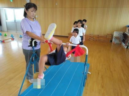 補助ひもを使って逆上がりの練習をしている