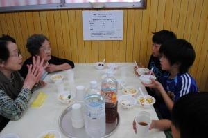 おばあさまと子どもたちが向かい合わせのテーブルで食事をしている写真