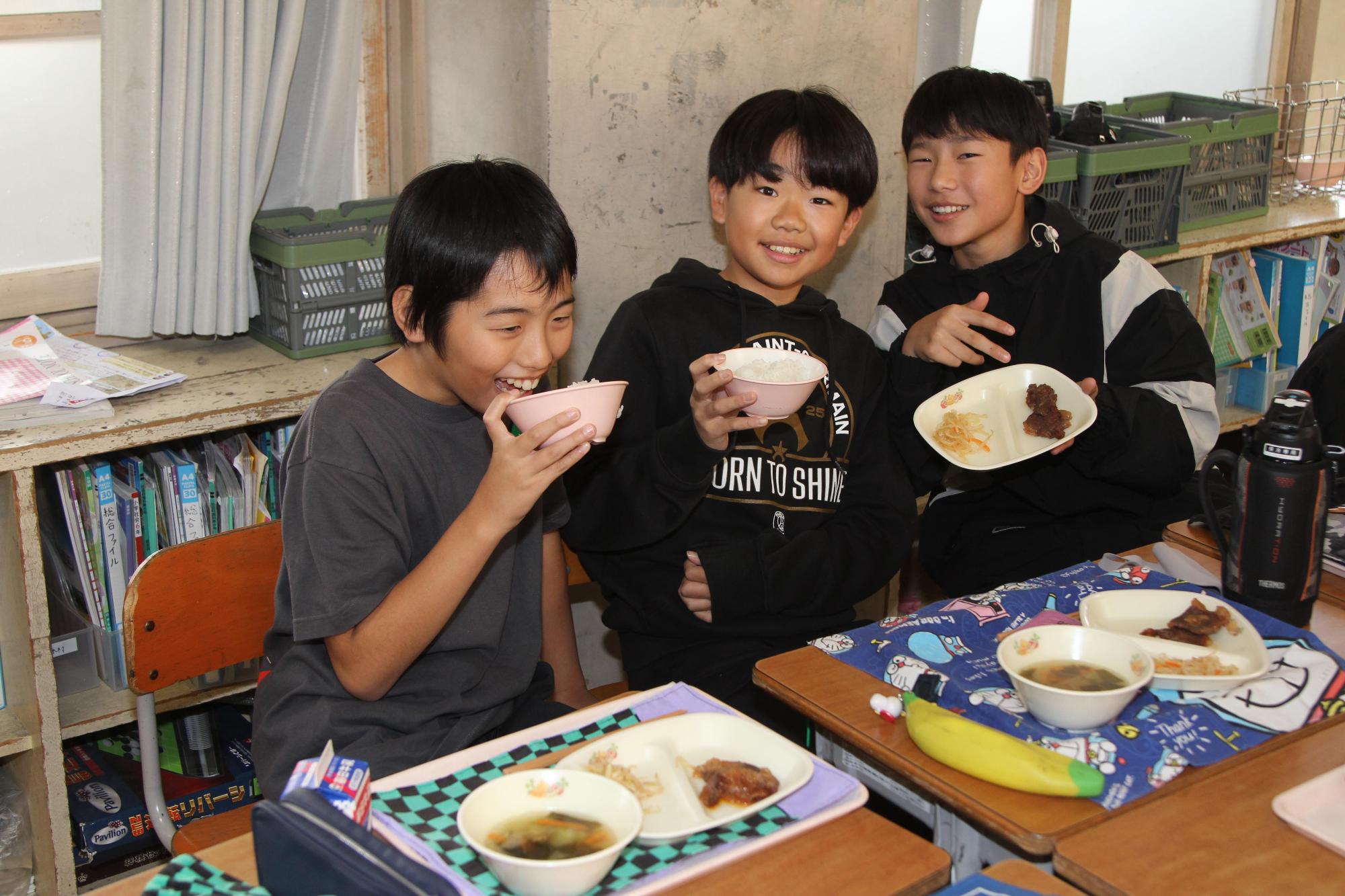 男の子3人が嬉しそうに給食を見せてくれている写真
