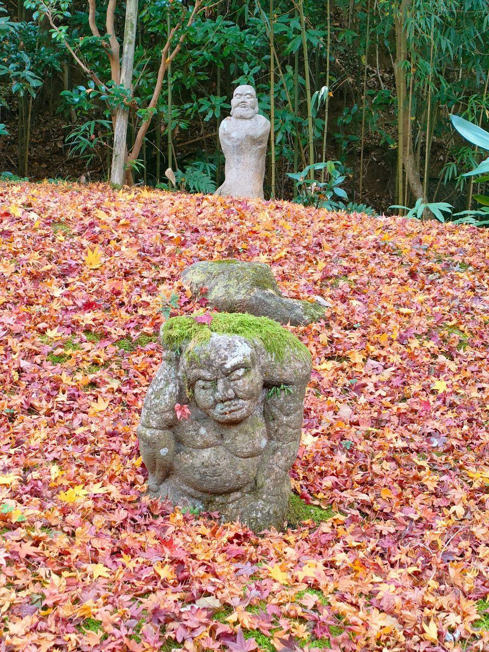 紅葉に囲まれた石像の写真