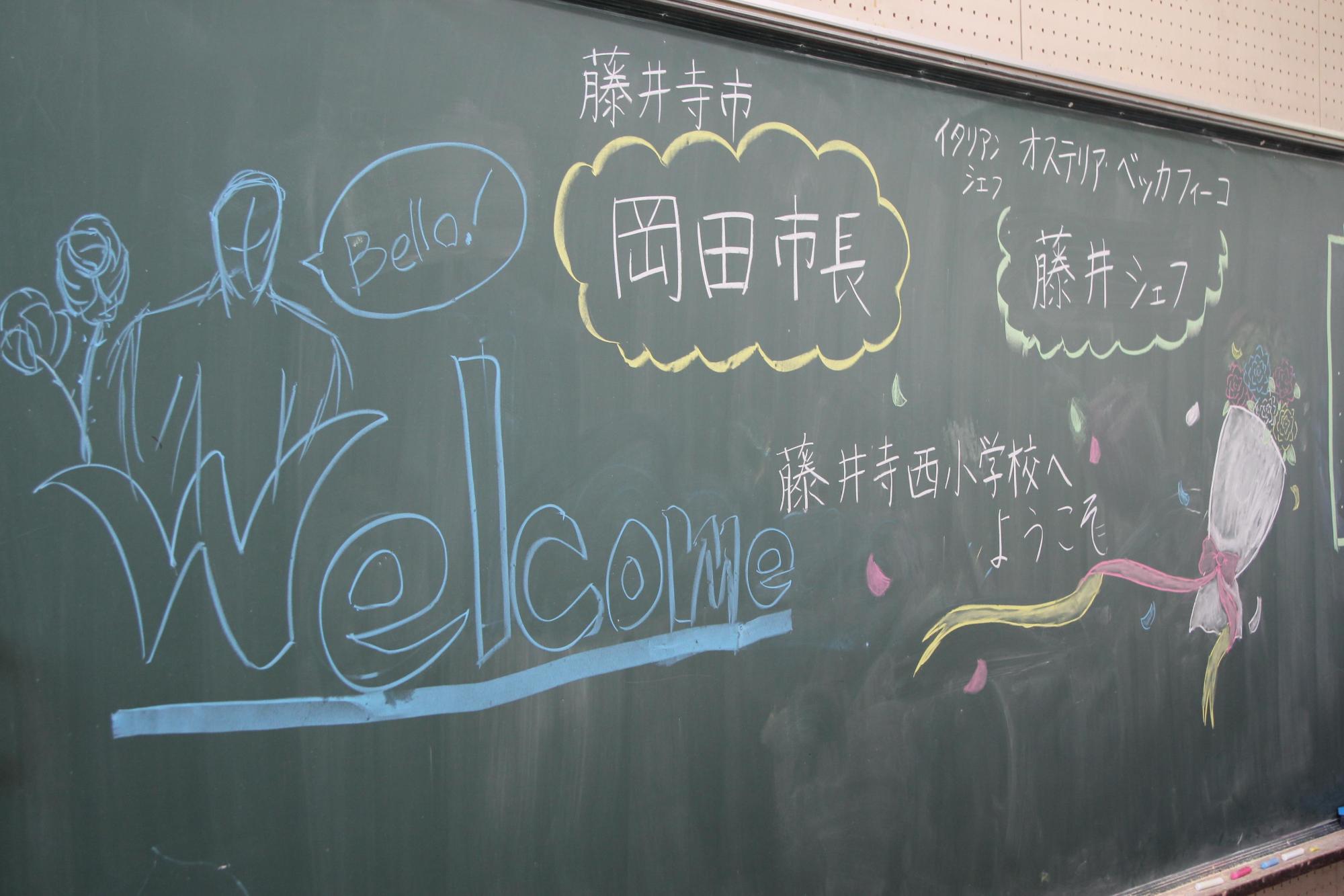 教室の黒板に書かれた藤井シェフと岡田市長へのウェルカムメッセージの写真