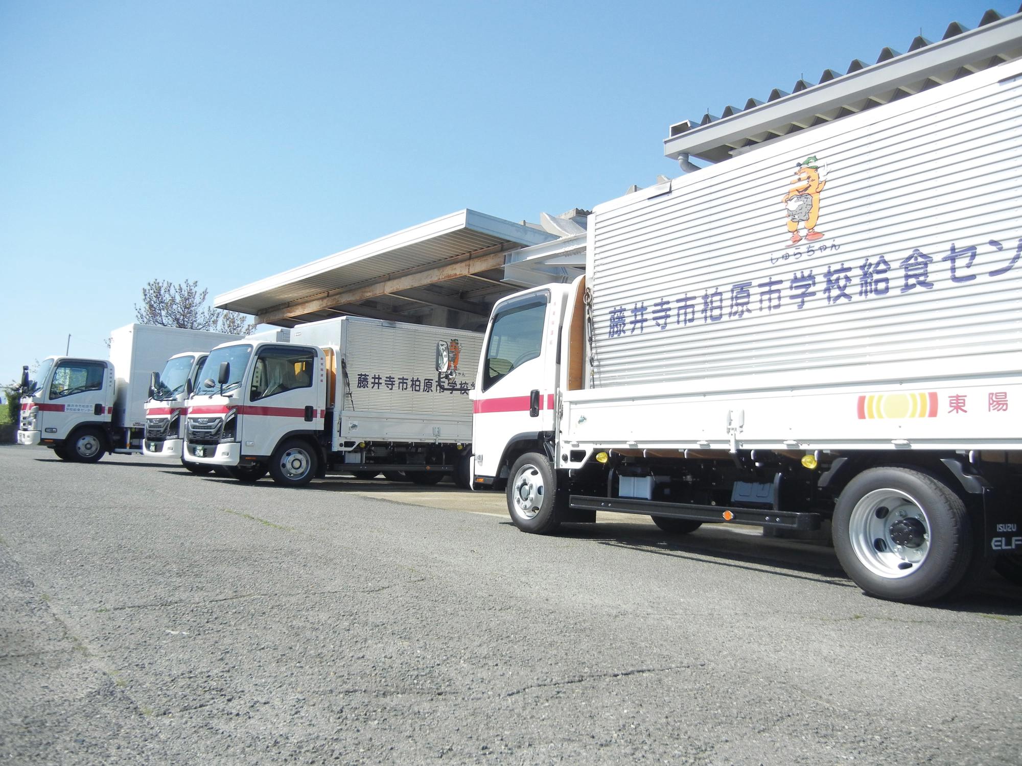 藤井寺市柏原市学校給食センターの前に配送用トラックがきれいに並んでいる写真