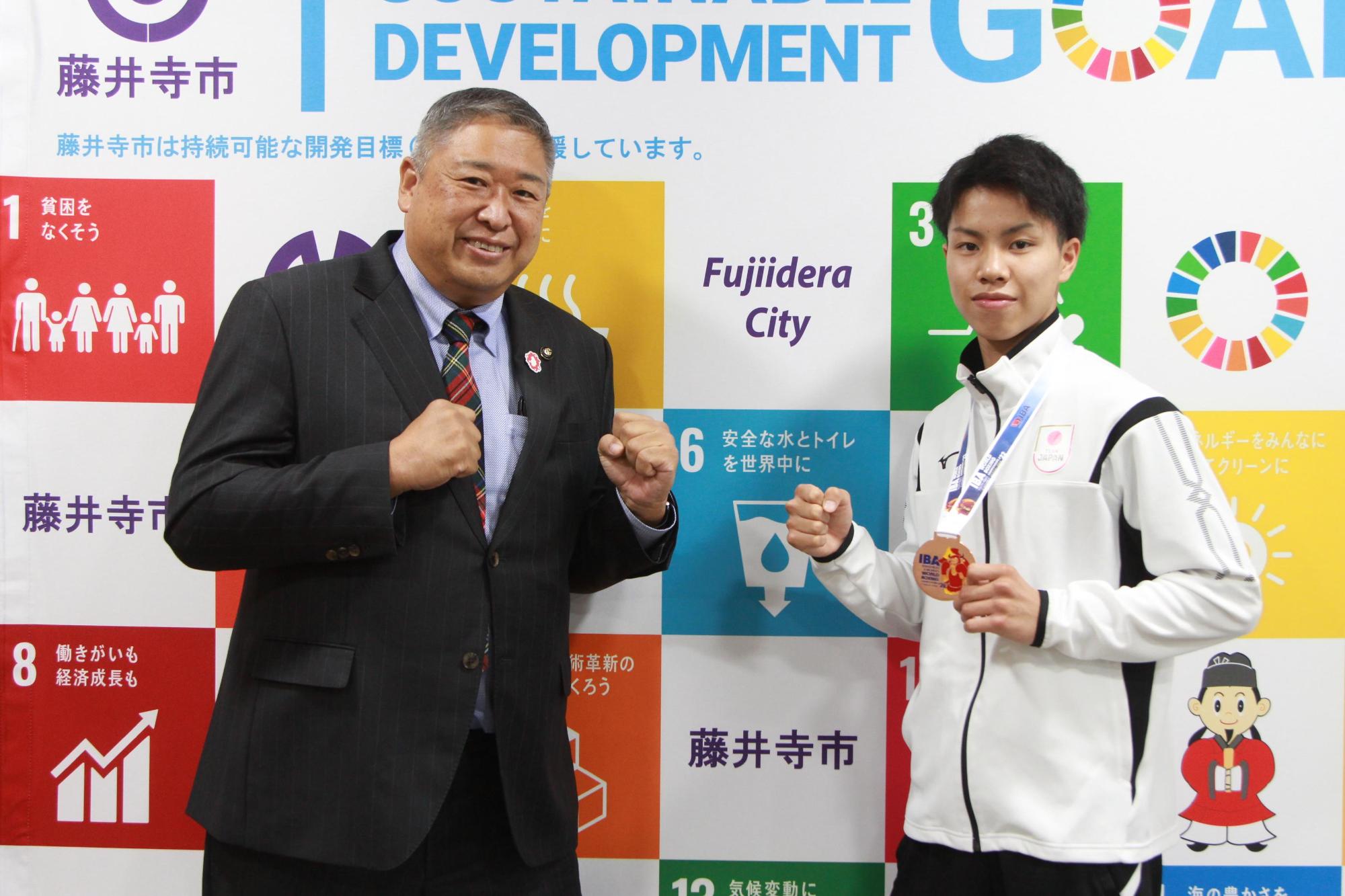 ボクシング世界ユース選手権3位に入賞した山口瑠さんと岡田市長がファイティングポーズをしている写真