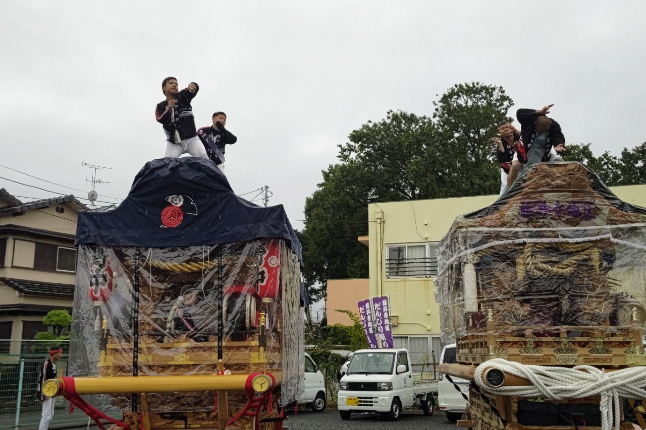 雨除けをつけているだんじり二台の写真