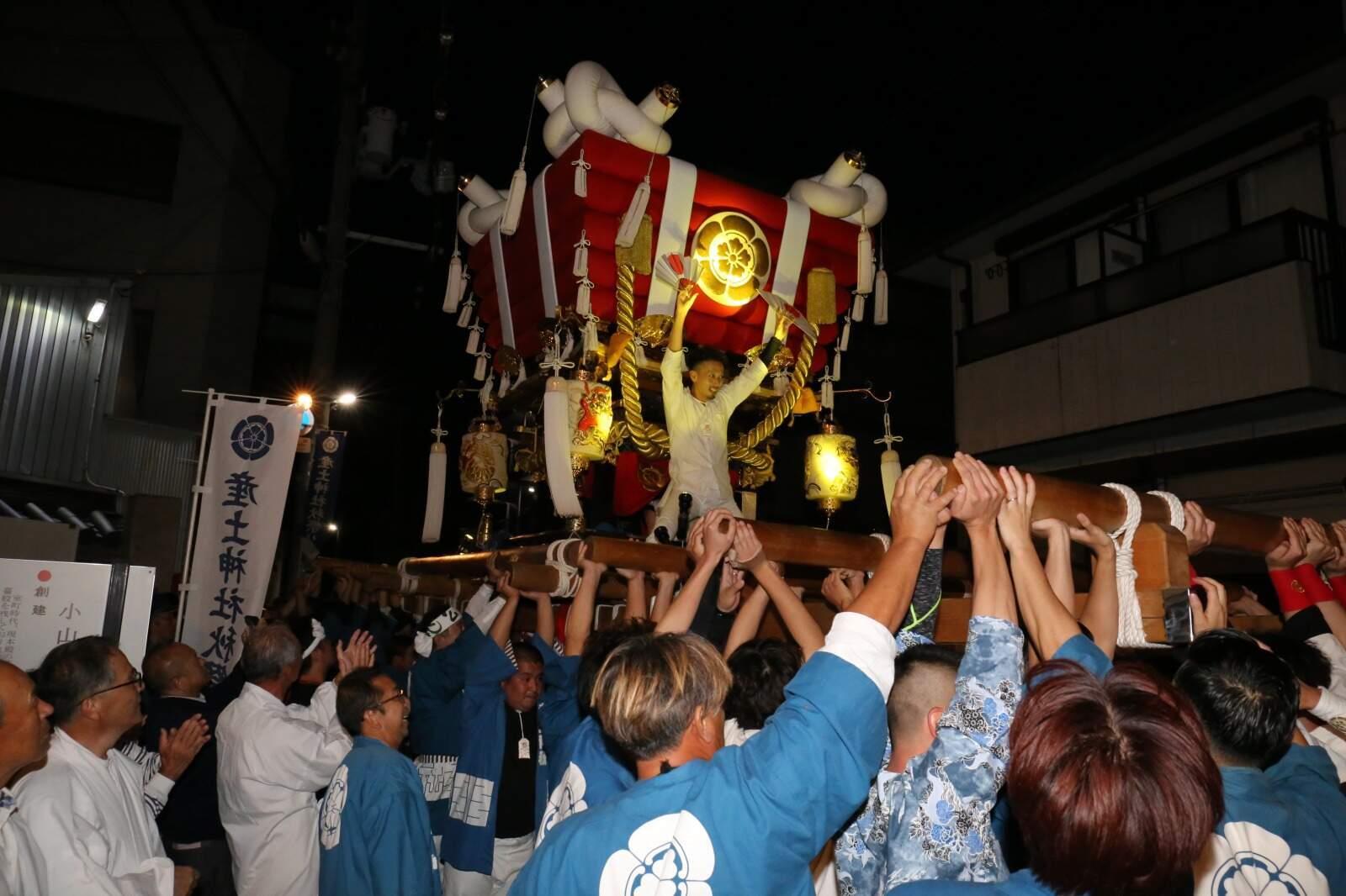 布団太鼓を担ぎ上げている人たちの写真