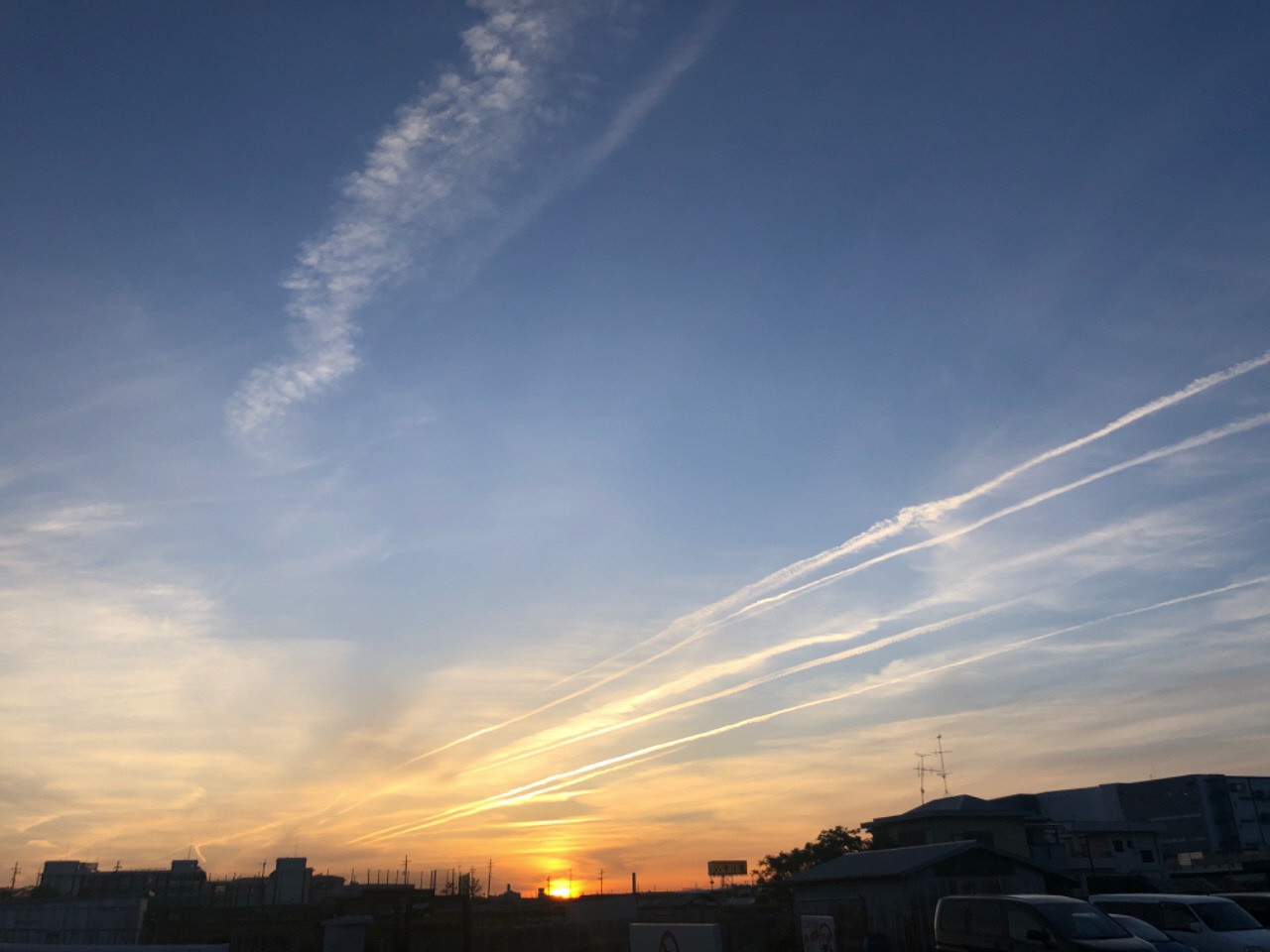 夕焼けの空一面に広がる飛行機雲の写真