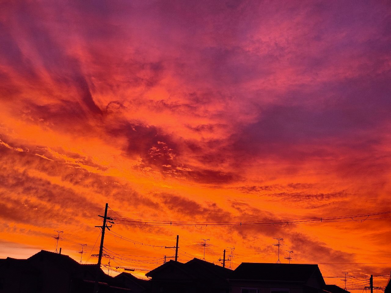 濃いオレンジ色の空に雲が立ち込める朝焼けの写真