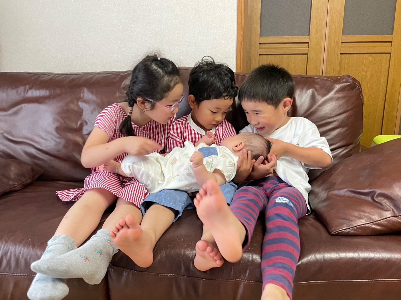赤ちゃんを3人のお子さんが抱っこしている写真