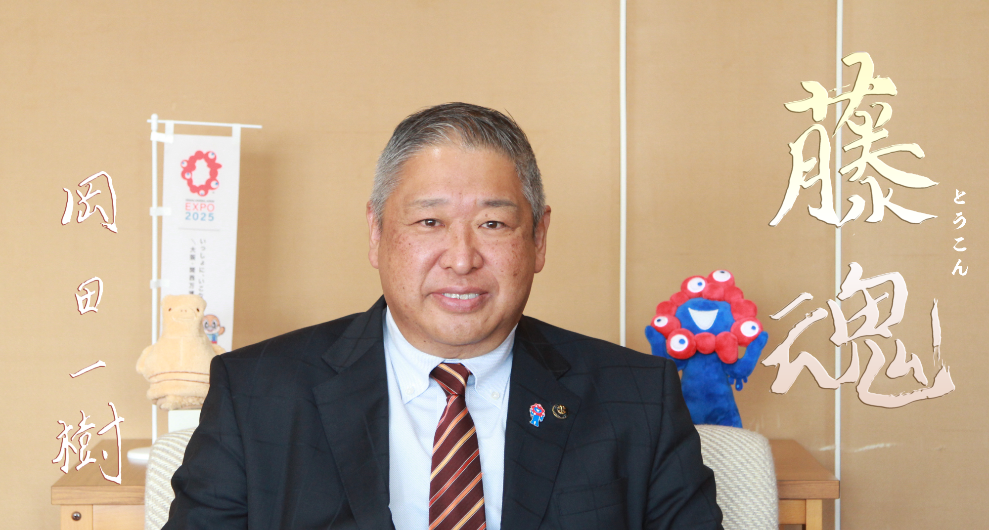 みずどりはにわとミャクミャクのぬいぐるみの間に座っている岡田市長の写真