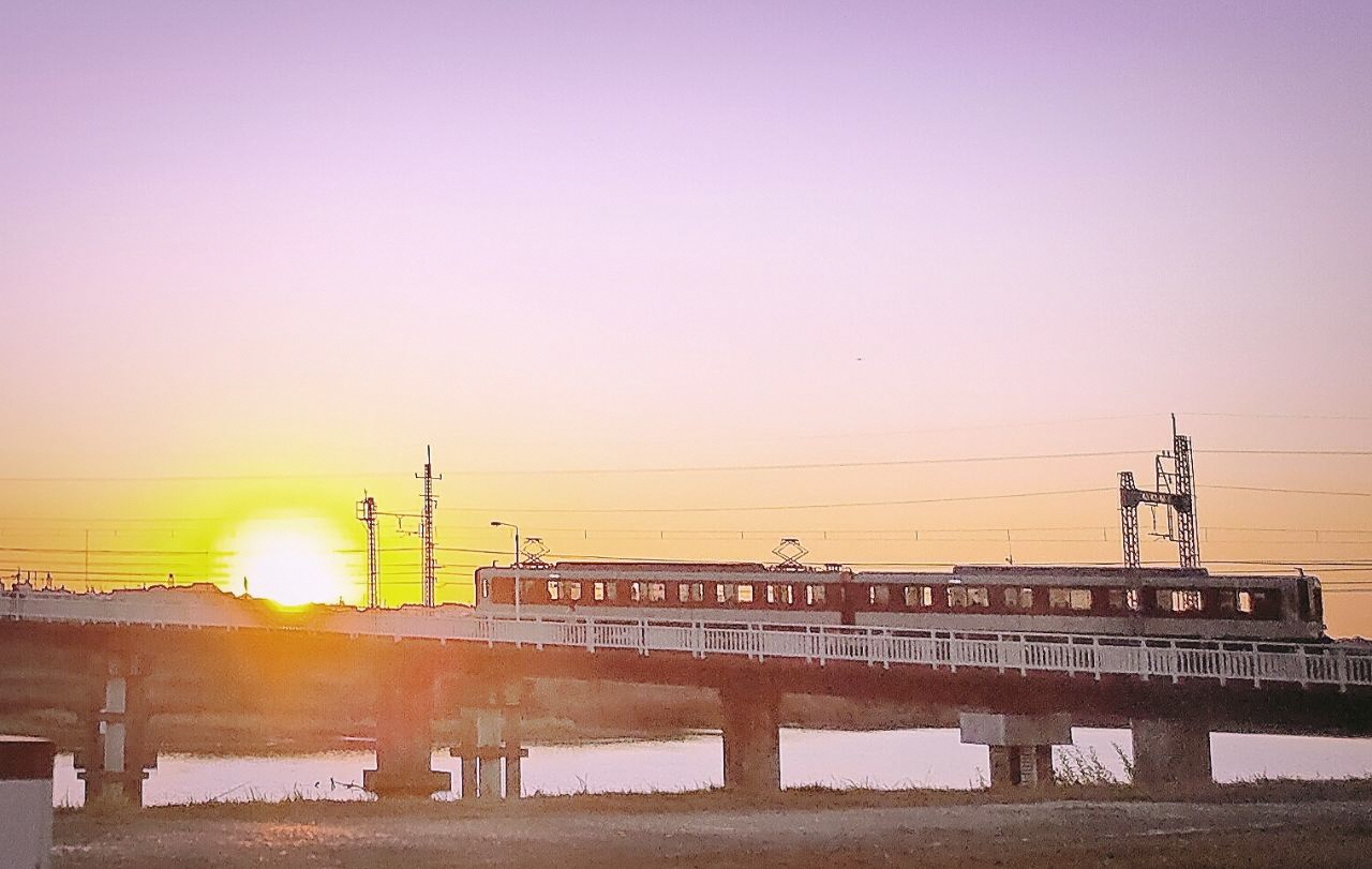 夕陽と近鉄道明寺線が橋の上を走っている写真