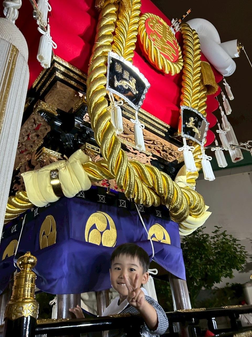 布団太鼓にのってピースをしているお子さんの写真