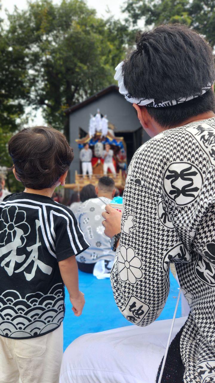 親子でだんじりを見ている後ろ姿の写真