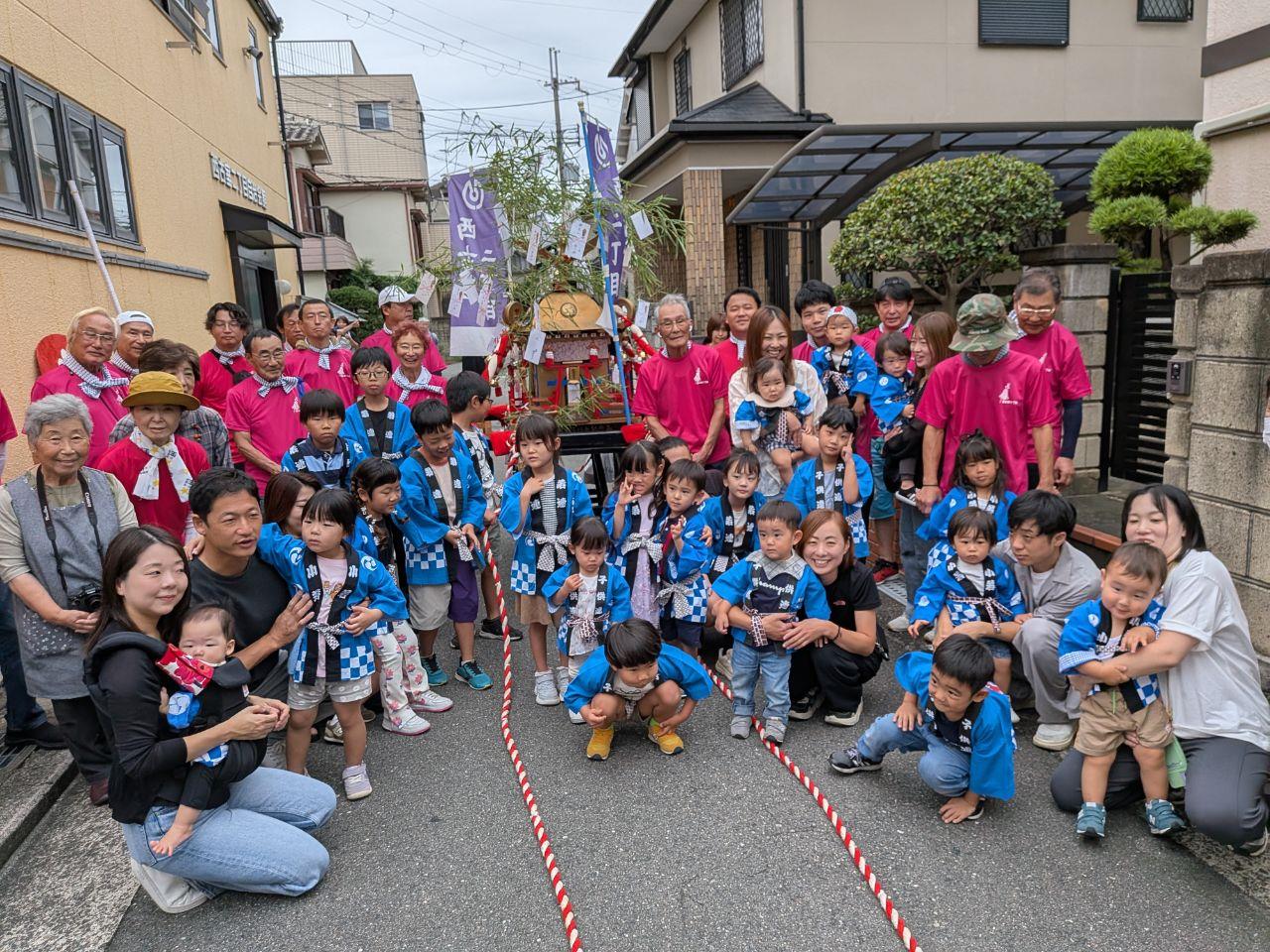 多くの人がお神輿の周りでわらっている集合写真