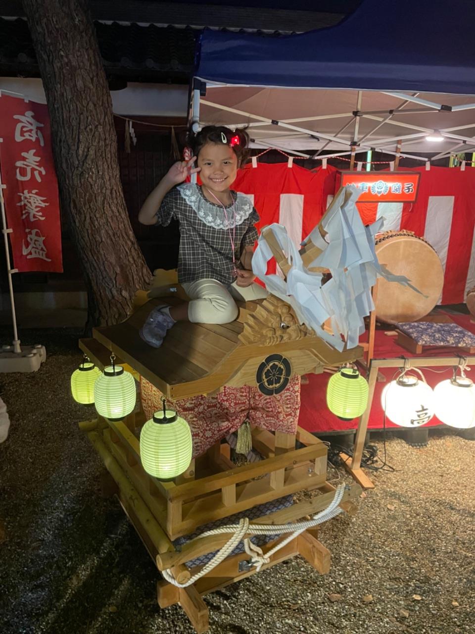 小さいだんじりの前でポーズをするお子さんの写真