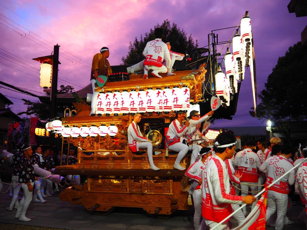 赤紫の夕焼けの下、大井地区のたんじりが進んでいる写真