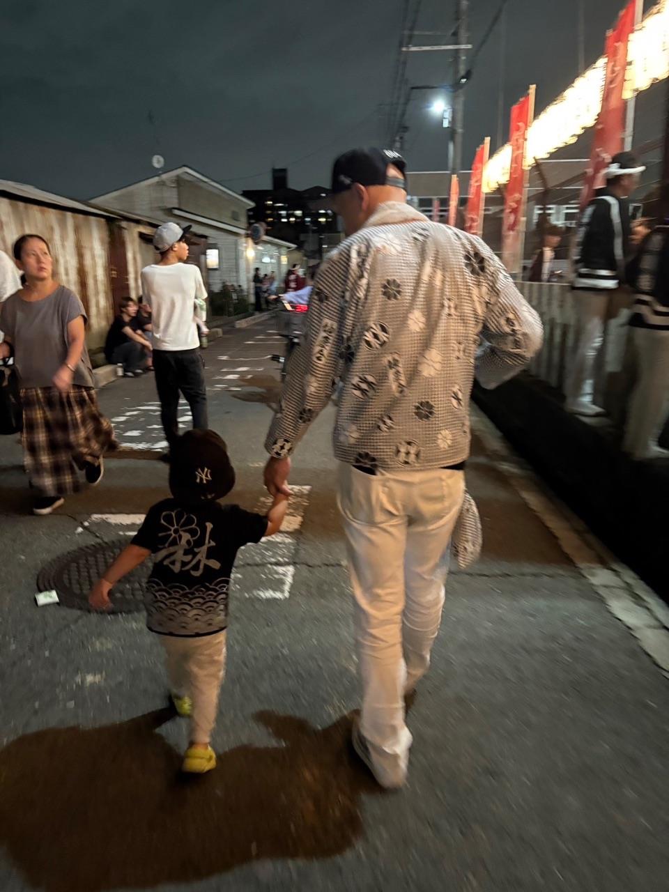 法被を着た小さい男の子とおじいちゃんが手をつないで歩いている様子