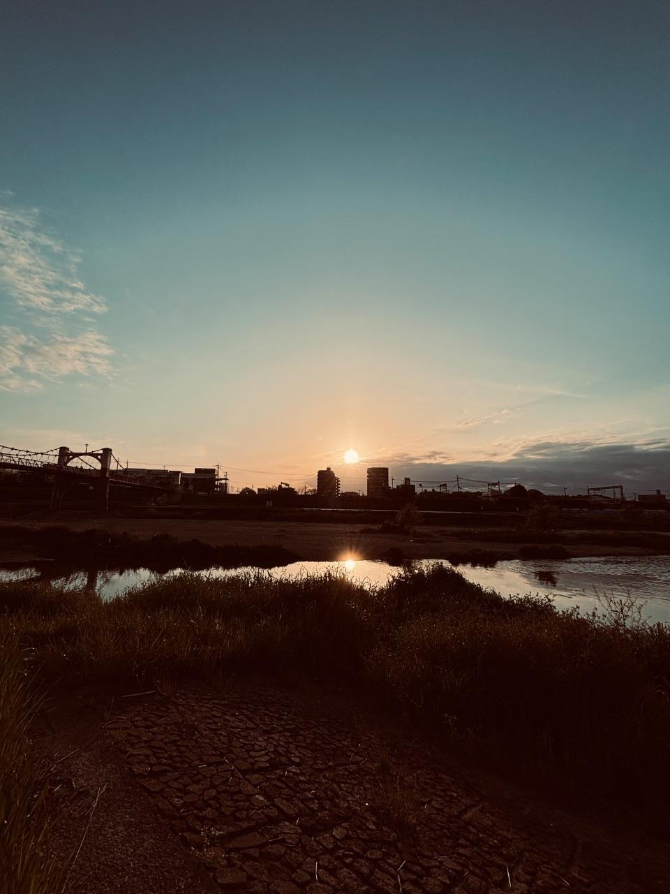 左側に玉手橋を望む石川河川敷から夕陽が見えている写真