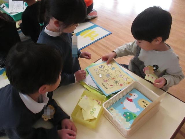 3歳児クラスの友達が出席カードにシールを貼るのを見守ってくれています。