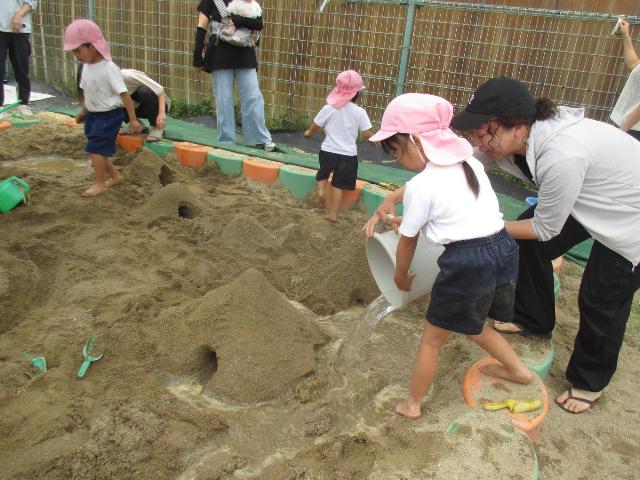 山の周りに作った道やトンネルにバケツで組んだ水を流しています。