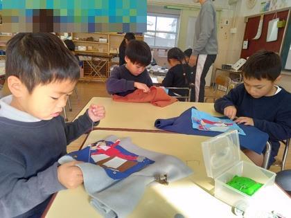 クリスマスをイメージして作ったアップリケを袋に縫い付けています。