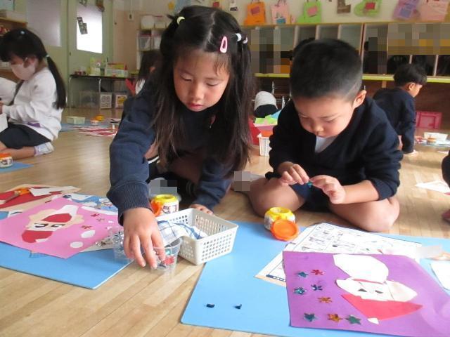 サンタの顔ができたら周りに雪を作って貼ったり、キラキラ折り紙の星や雪の結晶を貼ったりしながら袋をおしゃれに飾っています。