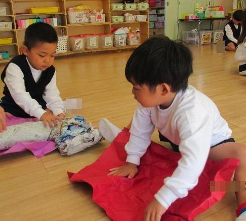 丸めてやわらかくなった画用紙を広げて、新聞紙で作ったものを包んでいます。