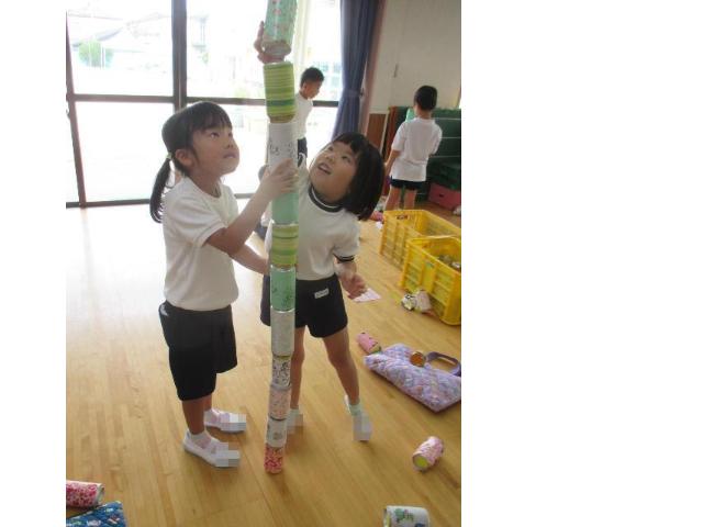 友達と協力して空き缶を高く積み上げています。
