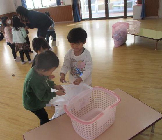新聞紙を固く握って、新聞のお団子を作り、ノンタンの袋に入れています。