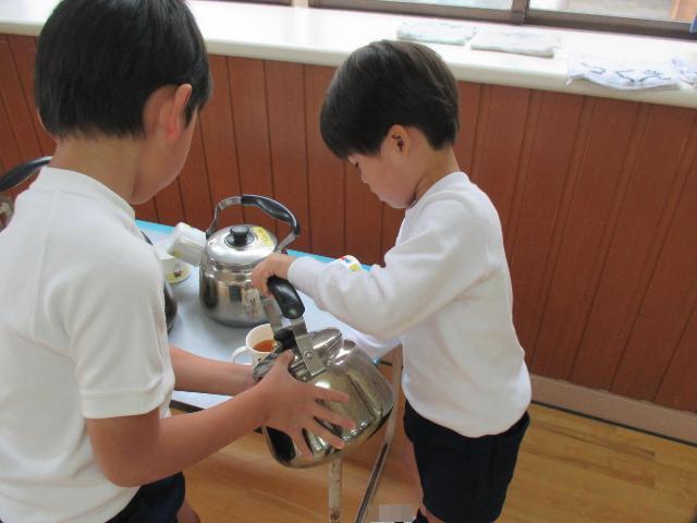 やかんのお茶をコップに注ぐのを手伝ってくれています。