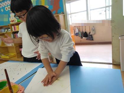 画用紙を半分に折って優しく押さえています。