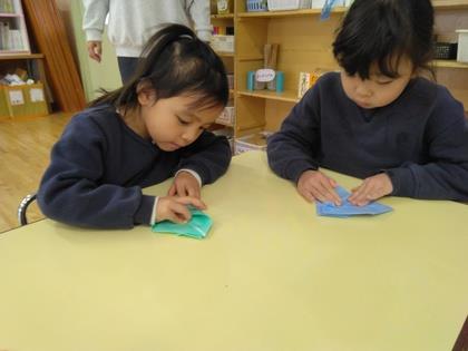 折り紙の端と端を合わせて丁寧に折っています。