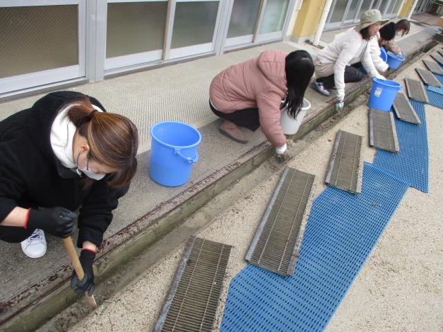 側溝のふたを外して中に溜まった泥やごみを取り除いて掃除をしています。