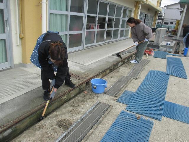 側溝にたまった砂や土を丁寧にかきだして綺麗にしています。