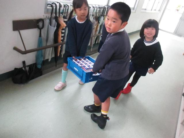 小学校の給食室から、食器や牛乳を運んでいます。