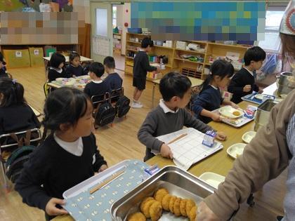 トレイを持って配膳台に並び、おかずの食器を順番にをのせています。