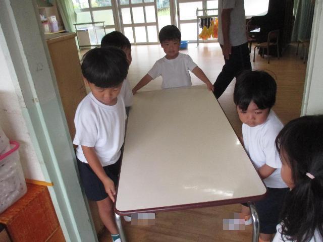 みんなで力を合わせて保育室の机を運び出しています。