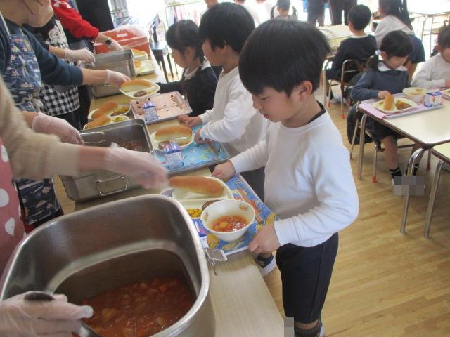 給食のトレイを持って配膳台に並んでいます。