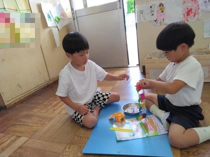 年少組が輪つなぎを作っているのを年長組が見守っている