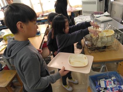 給食の片づけの仕方を教えてもらう様子