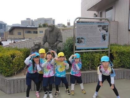 サルのオブジェの前で記念撮影する子ども